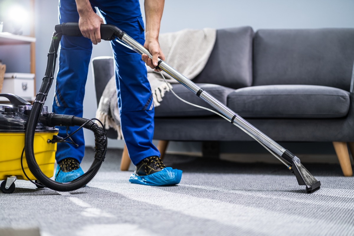 person cleaning carpet with vacuum cleaner